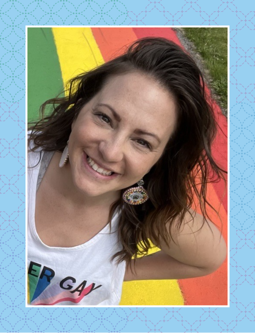 Amanda smiling at the camera with rainbow pavement in the background